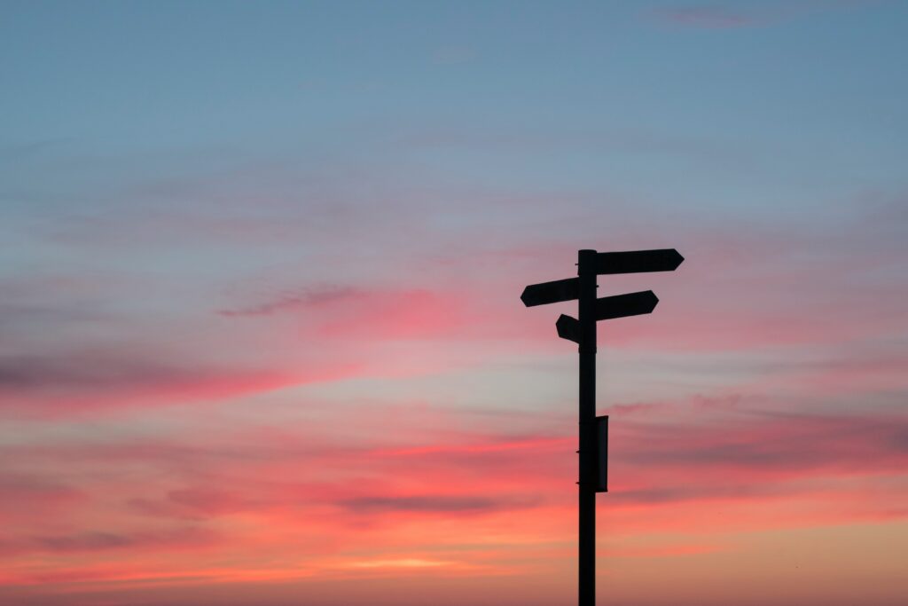 A sign giving directions shown in silhouette. Photo by Javier Allegue Barros on Unsplash